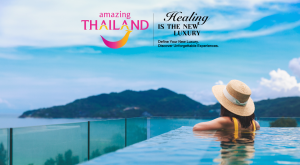 A traveler relaxes in an infinity pool overlooking Thailand’s coastline beneath the “Amazing Thailand – Healing is the New Luxury” campaign branding.