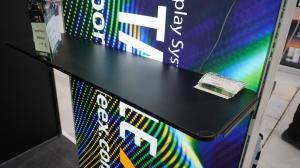 A portable booth by PortableX has a rack to install a desk on the frame.