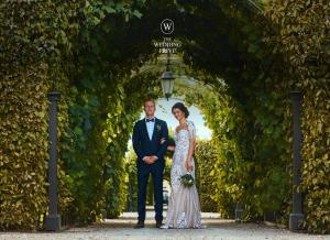 A bride and groom posing in a lush green garden archway representing ultra-luxury multi-destination weddings by The Wedding Privé.