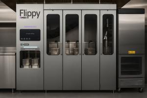 Image of an enclosed fry station with a robotic arm that manages fryer baskets