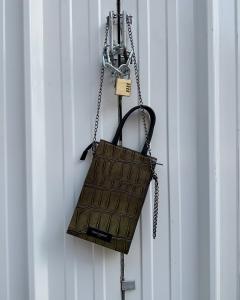Close-up of a premium olive green crocodile-embossed leather bag with silver chain details by designer Tony Grieco, illustrating high-end Parisian leather craftsmanship.