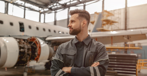 MRO or engineer posing in front of plane and exposed engine.