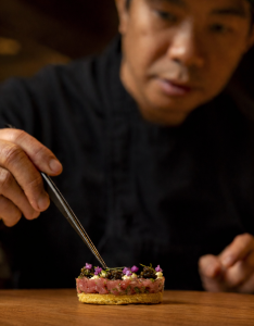 Chef JM Canlas carefully plating a micro-seasonal Japanese omakase dish at MINŌ in Boca Raton.