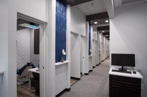 Interior hallway showing multiple dental operatories at Optum Dental Arts in Tampa following a 60% expansion in clinical capacity.