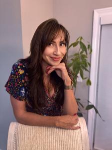 Professional headshot of author Maritza Perez smiling, wearing a dark blazer and white top against a neutral background.