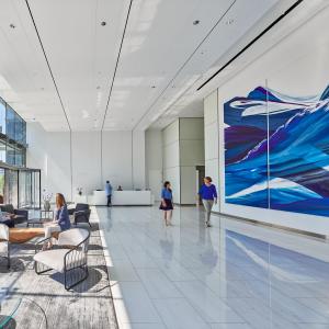 A major, large scale painting in many blue tones, resembling waves in a light filled, grand lobby. .