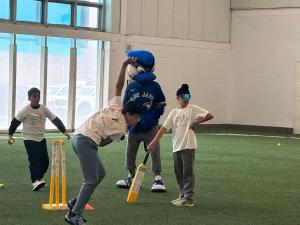 ACE, the Toronto Blue Jays mascot, plays cricket with OSCA students during a youth activity at the OSCA Cricket-Ed Forum 2026.