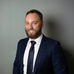 Professional portrait of Phil Neil, Montreal-based serial entrepreneur and TEDx speaker, wearing a navy suit and tie.