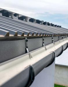 Close-up of a newly installed black metal gutter system on a residential roof in Vacaville, CA, showcasing professional mounting brackets and clean alignment.