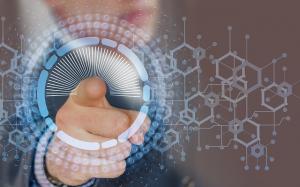 Semi-close-up of a male professional pointing at a holographic-style digital screen, representing telehealth technology and virtual patient care.