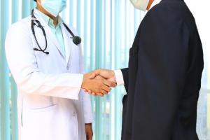 Male doctor shaking hands with a professional, symbolizing trust, partnership, and patient-centered healthcare.