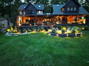 Large custom deck with black railing, covered outdoor living areas, integrated lighting, and landscaped backyard behind a two-story home