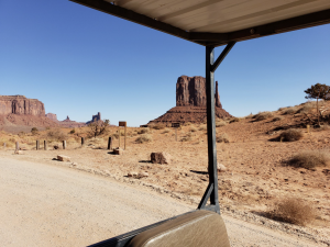 Roadside view of Monument Valley with prominent buttes visible in the distance.
