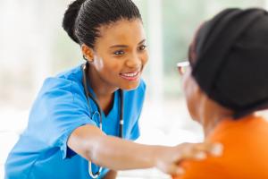 photo of a health care professional in blue scrubs touching a client on a the shoulder with empathy