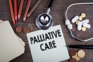 photo a table with stethscope, pills and some health care supplies laying on it with large letters that read Palliative Care