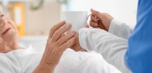 photo a palliative care client in a hospital bed with a nurse providing care