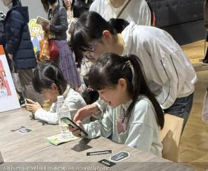 Girls enjoy virtual makeup on a smartphone.