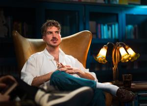 Joey Graceffa reflects on the impact of The Subtle Knife while reclining in a leather library chair.