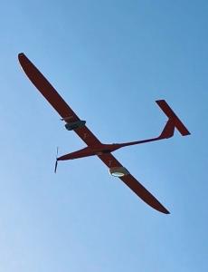 A drone flying in the sky with a wireless power beaming receiver attached