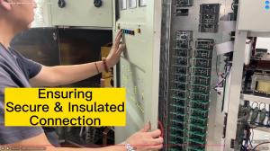 Man in black t-shirt with red bracelet pushes a color button on the control panel of an AM transmitter. Right side is a rack with stacked PCB power modules featuring many green LEDs. Large yellow text box says, 