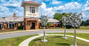 Exterior of Prince Michel Winery in Leon, Virginia, featuring a brick entrance tower, landscaped grounds, and modern metal sculptures under a blue sky.