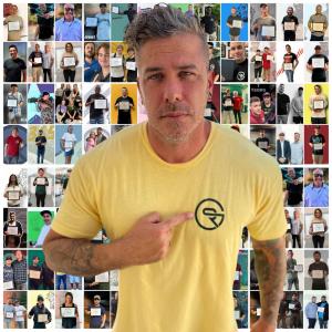 Tom Fay standing in front of hundreds of photos of Gambit Recovery residents who earned 90-day recovery milestones