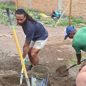 Avonte Maddox, a defensive back for the Detroit Lions, and his friend Xavier Cornelius are using shovels to help build a cement floor on a service trip with Grace Community Church and International Samaritan.