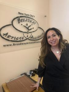 Alycia Kaback, Co-Founder of VIP Ignite, smiles and poses in front of the New York City Broadway Artists Alliance logo and signage, reflecting the deep industry relationships and two decades of entertainment connections she has built as one of the most re