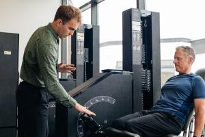 Exercise physiologist coaching a client on a leg press machine during a 30-minute strength training session at Discover Strength Draper in Utah