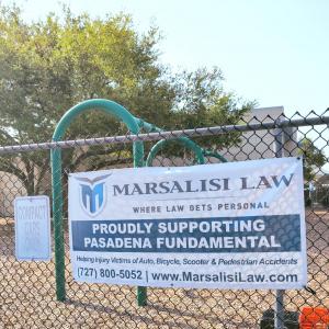 Marsalisi Law, a personal injury law firm deeply rooted in the St Marsalisi Law sponsorship banner displayed on a chain-link fence at Pasadena Fundamental Elementary School in St. Petersburg, FL