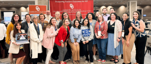 The Zarrow Institute on Transition & Self-Determination Strengthens Commitment to Accessibility with CAC Renewal 17 Group photo of diverse adults standing in front of a red Zarrow Institute banner at an indoor event promoting positive outcomes.