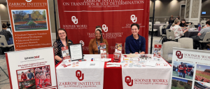 The Zarrow Institute on Transition & Self-Determination Strengthens Commitment to Accessibility with CAC Renewal 19 Three people sit behind a University of Oklahoma Zarrow Institute and Sooner Works informational booth at an indoor event.