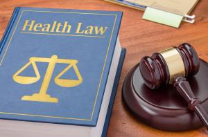 The American Institute of Health Care Professionals Offers a Medical Malpractice Consulting Certification Program 22 photo of a health care law text book with the scales of justice beside it