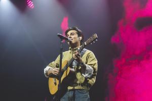 Anuv Jain performing live with an acoustic guitar at Big Night Live in Boston during the Dastakhat World Tour 2026, illuminated by stage lights during his sold out North American concert tour.
