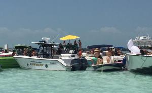 Fort Lauderdale sandbar area with boats anchored in shallow turquoise water and people gathered for a social boating scene.