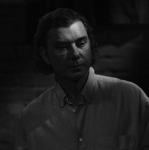 Musician Gavin Rossdale, photographed in dramatic black-and-white, stands in a library.
