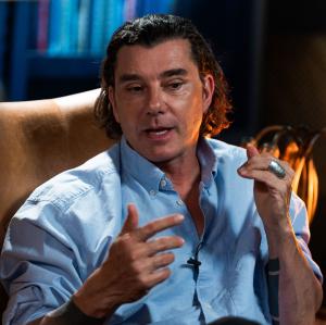 Musician Gavin Rossdale speaks while seated in a brown, leather high-backed library chair.
