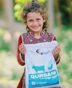 Al Mustafa Welfare Trust Qurbani 2025 meat distribution, young girl receiving Qurbani donation package on Eid al-Adha, delivered by Al Mustafa Welfare Trust UK