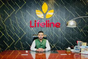 Dr. Fazal Wahid seated at his desk in the Lifeline Rehab Center, with the center's logo in the background.