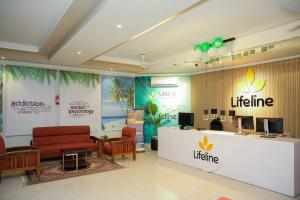 Interior of Lifeline Rehab Center with seating, tropical-themed wall art, and the center's logo at the reception.