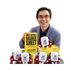 James C Foo Leong smiling while holding Once Upon a Balance Sheet, with Count Jargon plushies displayed in front of him.