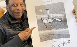 Pele holding up one of his Hand-Signed Signature Sheets