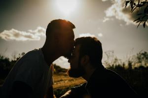 Silhouette of two men sharing a tender moment at sunset, representing Asana Recovery's couples program for LGBTQ+ partners in recovery together at the Orange County facility.