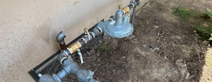 Exterior view of a professional natural gas regulator and piping assembly installed alongside a residential building foundation, showcasing the precise utility infrastructure work provided by KPS Plumbing.