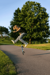 Photographer and artist Lindsey J High school senior performing a skateboard trick on a paved path during an outdoor portrait session at sunset in Central Pennsylvania.