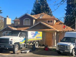 Residential home undergoing roof installation with a Cloise & Mike Construction work truck in the driveway.