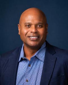 Professional headshot of Kevin D. Williams, Dallas-based Communication Strategist and bestselling author, in navy blazer against navy background.