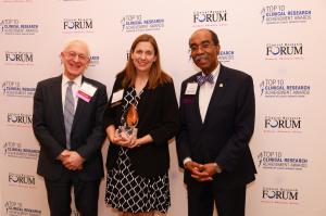 The Clinical Research (CR) Forum, a non-profit membership association of top clinical research experts and thought leaders from the nation’s leading academic health centers, awarded its most prestigious honor, The Herbert Pardes, MD Clinical Research Excellence Award, to Dr Two men in suites are standing on either side of a woman in a dress. From left to right, the people are Dr. Harry Selker, Clinical Research Forum chair, Dr. Rebecca Ahrens-Nicklas, who is holding a statuette award, and Dr. E. Albert Reece, Clinical Resea