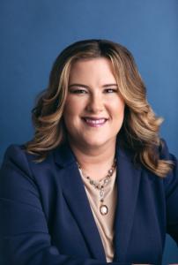 Professional headshot of Whitney Pennington, founder of Pennington Law Firm, smiling confidently in a navy blazer against a blue studio background, reflecting her compassionate and professional approach to legal advocacy