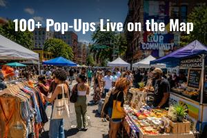 Busy outdoor urban pop-up market on a city street with vendors selling handmade empanadas, vintage clothing, and art to a diverse crowd, with the text